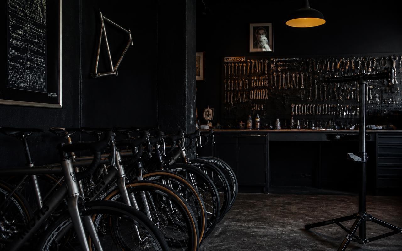 Dark bicycle shop interior with steel road bikes and a wall of tools